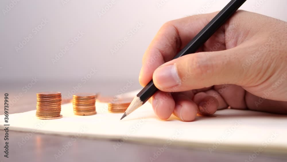Poster a male hand writing on a notebook with stack of coin for business and financial.