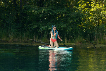 Woman with blue braids sitting on an inflatable boat on river and holding a paddle