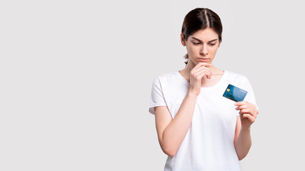 Bank deposit. Financial crisis. Doubtful woman with credit card concerned about money safety isolated on white copy space. Cashless payment.
