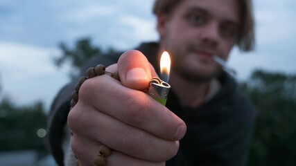 Man on the street lights lighter rack focus. The guy brings lighter to the camera and gives you...