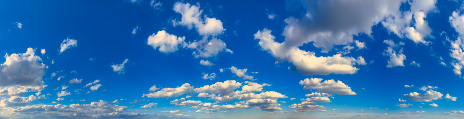 Fototapeta premium White cumulus clouds in blue skies at high altitude in daylight in the afternoon. Ultra wide panorama.