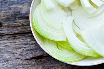 Sliced white onion in a saucer on a wooden Board