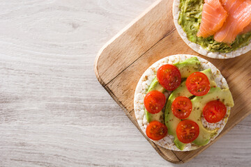 Assortment of ingredients on puffed rice cakes on white wooden table.Top view.Copy space