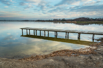 Long wooden bridge on a lake and evening clouds