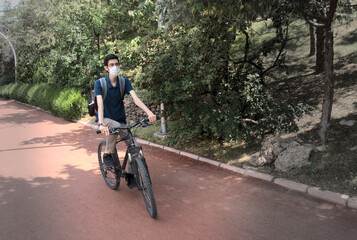 Obraz premium Isolated, skinny young male wearing a mask cycling on a bicycle path at a park