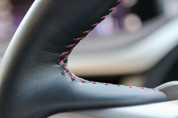 Close up of a car steering wheel with red stitching