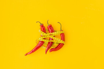 red pepper and measuring tape on yellow background.