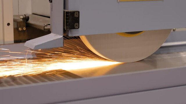Automatic cnc surface grinding wheel machine working with sheet metal with sparks at factory, plant. Metalworking, machining, industrial, equipment, technology, manufacturing concept