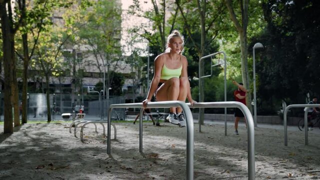 Authentic close up caucasian girl with blonde ponytail wearing green top doing knee raises or abs on parallel bars
calisthenics, street workout, fitness, nature
