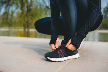 closeup view of woman's hands in sport suit tying up shoelaces on her sport sneakers while running...