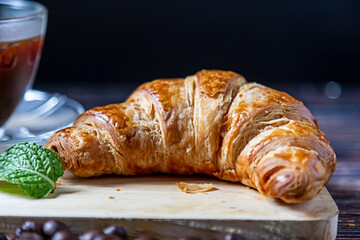 Croissant with mint leaves to decorate on the wood.
