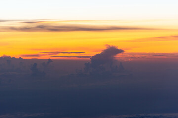 View from the plane window to the evening sky. Beautiful sunset from the plane window. Flying above the clouds. Orange and purple warm shades of the sky.