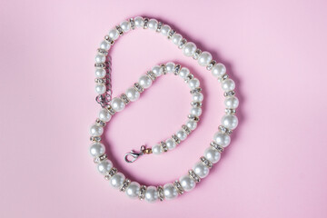 White pearl decoration on a pink background. Women's accessory. Glamorous decoration
