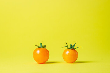 Yellow tomatoes on a yellow background. Ripe juicy tomatoes. Tomato variety. Two tomatoes stot next to each other
