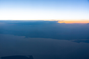 View from the plane window to the evening sky. Beautiful landscape from the plane window. Flying above the clouds. Warm blue shades of the twilight sky.
