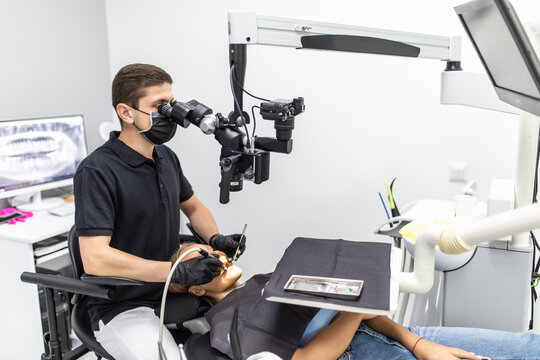 The dentist examines the patient's teeth with a dental microscope. Modern medical equipment