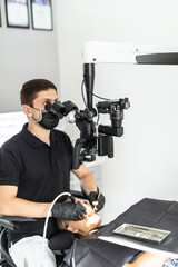 Male dentist examining woman looking on the teeth with professional microscope in the dental office