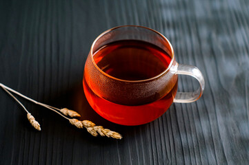 black tea in a transparent Cup next to a spike on a dark wooden background