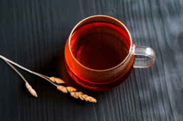 black tea in a transparent Cup next to a spike on a dark wooden background
