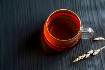 black tea in a transparent Cup next to a spike on a dark wooden background
