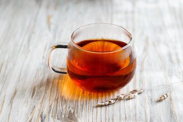 black tea in a transparent Cup next to a spike on a light wooden background