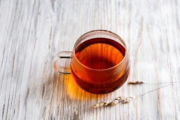 black tea in a transparent Cup next to a spike on a light wooden background