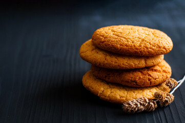 oatmeal cookies next to a spike on a dark wooden background