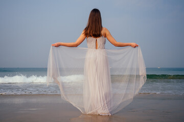 Fototapeta na wymiar woman in amazing white bride wedding dress feeling free and happy yo be at ocean