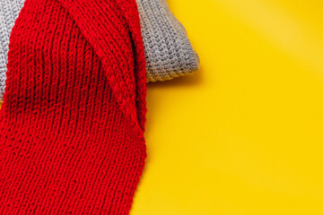part of a grey sweater and red scarf on a yellow background, copy space