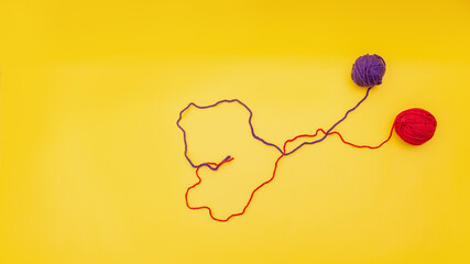 heart of red and blue thread, unraveled from a tangle on an orange background