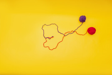 heart of red and blue thread, unraveled from a tangle on an orange background