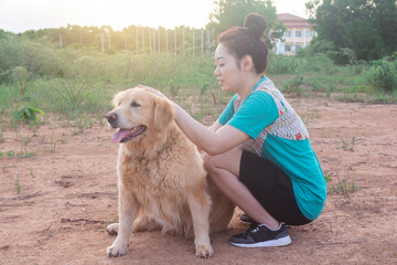Asian woman playing with her golden retriever dog in a park outdoors