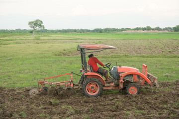 Tractor working plows a field on the farm for planting.