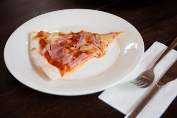 hawaiian pizza with ham, pepperoni, tomatoes on wooden table