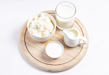 Obraz na płótnie Canvas Grain cottage cheese, sour cream, cream and milk on a wooden round stand in a high key