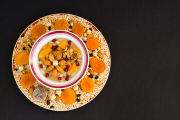 Traditional Turkish Dessert Ashure or Noah's Pudding designed flower shape in white bowl on black surface with copy space