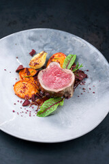 Gebratenes dry aged Angus Filet Steak natur vom Rind mit Kartoffel und Gemüse Chips angeboten als close-up auf einem Modern Design Teller