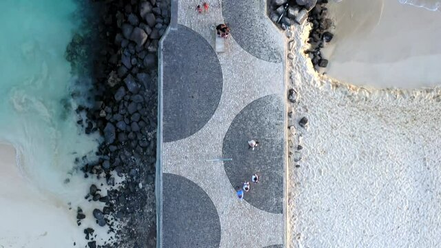 Aerial top down shot of the famous Santa Maria wooden pier, on the island of Sal, Cabo Verde. Camera tracks along the pathway and the pier is revealed.