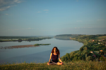 Fototapeta premium Yoga practice and meditation in nature in sunrise. Woman practicing near big river Kama.