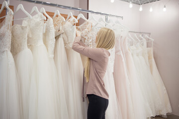 young blonde woman chooses a wedding dress in a wedding salon.