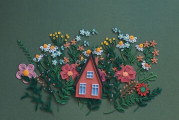 The house on beautiful flowers designs isolated on green paper background. Hand made of paper quilling technique
