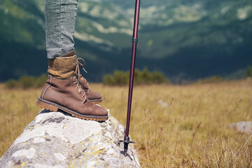 woman with leather boots and hiking stick on mountain