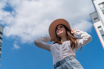 Portrait of a beautiful caucasian woman outdoors against a blue sky background. A girl wearing a hat and walking shorts on a hot summer day.