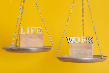 Work and life balance concept. Balance scales on yellow background, close up