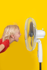 Child with ventilator on yellow background. Vertical frame. Hot summer