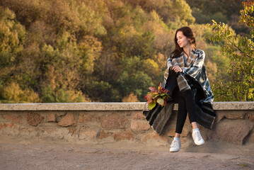 Pretty girl sit on the roadside on the background of nature. Travel in the autumn