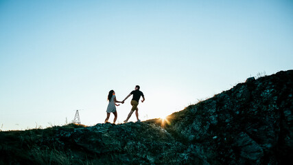 silhouette of a man and a woman in the open air, two young people in nature, silhouette at sunset