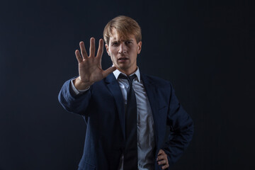 Stop it, a young male businessman in a suit and tie makes a gesture of protest.