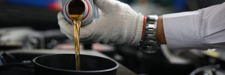 Close-up hands in gloves pour oil into car tank. Selection engine oil. Necessary volume of filling....