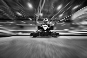 The man in a helmet in the go-kart moves on a karting track - obrazy, fototapety, plakaty